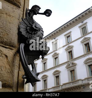 Ala metà uomo metà drago portacandele e cavallo post di aggancio sul muro di pietra di una strada a Firenze Italia Foto Stock