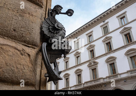 Ala metà uomo metà drago portacandele e cavallo post di aggancio sul muro di pietra di una strada a Firenze Italia Foto Stock