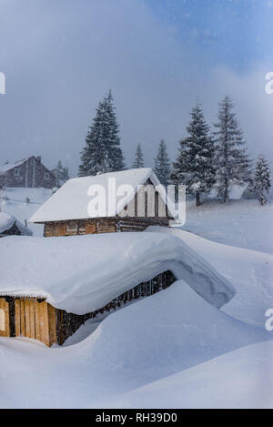 Fantastico paesaggio invernale con casa in legno in montagna innevata. Foto Stock