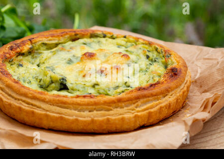 Close-up di quiche con verdure fresche. Sfocati con sfondo bokeh in toni di verde. Rustico e aspetto del paese. Foto Stock