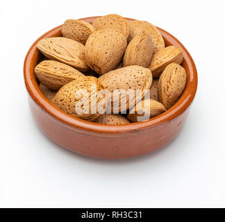 Mandorle con guscio nel recipiente di argilla (raccolta di vari dadi). Isolato su sfondo bianco. Foto Stock