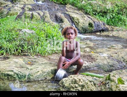 Ragazzo Ni-Van lavaggio piatti nel flusso Foto Stock