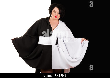 Incantevole donna grassa in un bellissimo nero e abito bianco su nero e sfondo bianco Foto Stock