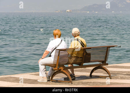 LAZISE, LAGO DI GARDA, Italia - Settembre 2018: due persone seduta su una panchina sul lungomare di Lazise sul Lago di Garda. Foto Stock