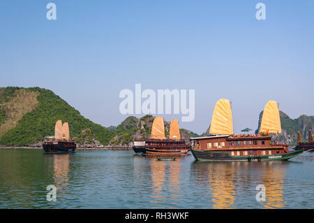 Più in legno barca indesiderata navi da crociera ancorato in Halong o la baia di Ha Long con calcare isole carsico in background, Vietnam Foto Stock