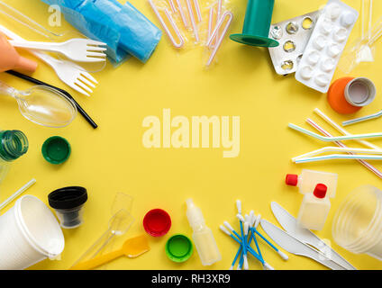 White a uso unico in plastica e altri oggetti in plastica su uno sfondo giallo. Il concetto di scelta senza plastica o i problemi ambientali. Foto Stock