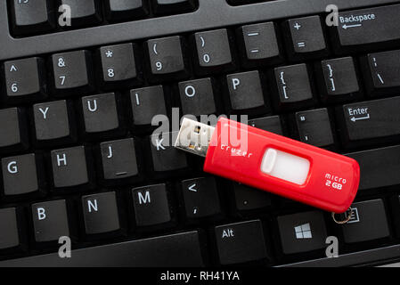 Un nero della tastiera del computer con un rosso cruzer memory stick per la memorizzazione di dati o memoria aggiuntiva. Foto Stock