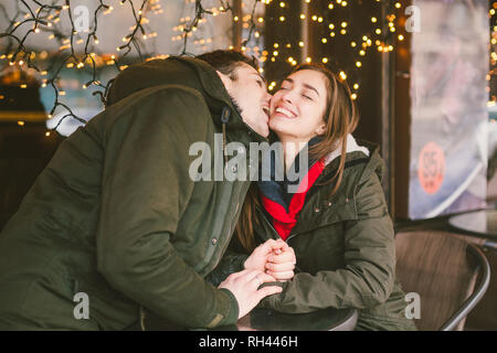 Tema amore vacanza San Valentino coppia studenti del college, eterosessuali caucasica amanti in inverno, sit tabella di street cafe contro lo sfondo di win Foto Stock