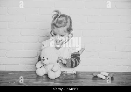 Ragazzo giocare medico con Teddy bear sul muro bianco. Bambino veterinario esamina toy animale con stetoscopio. Gioco, lo sviluppo, l'immaginazione. Futuro professi Foto Stock