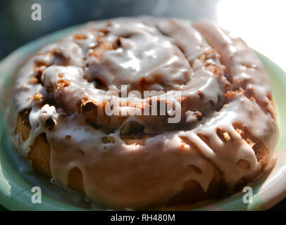 Un caldo rotolo alla cannella pasticceria si siede su una piastra a Faro panificio Dauphin Island, Alabama. Foto Stock