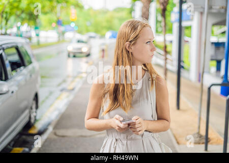 Donna che utilizza phone app per taxi salutando il servizio o tramite Phone app per trovare le indicazioni stradali e la guida durante il viaggio. Ragazza turista su strada Foto Stock