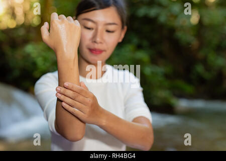 Un repellente per le zanzare. Le donne usano repellente per insetti crema nella foresta. Foto Stock