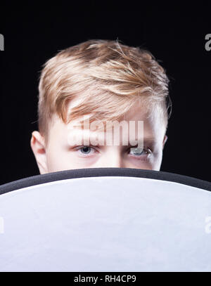 Ragazzo con luce marrone capelli guardando sopra la parte superiore di un panno circolare Foto Stock