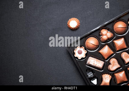 Vista ingrandita della scatola di cioccolatini con varietà cioccolatini praline, vista da sopra lo sfondo blavk Foto Stock