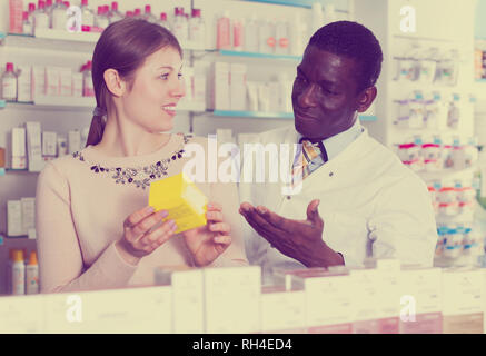 African American farmacista spiegando la medicina prescritta alla giovane donna in farmacia Foto Stock