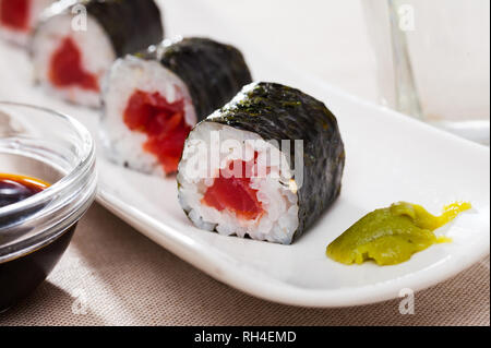 Tonno fresco maki sushi servita su piastra bianca con wasabi e salsa di soia Foto Stock