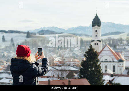 NESSELWANG, Germania - Dicembre 2018: Donna di scattare una foto di Nesselwang città vecchia al mattino. Foto Stock