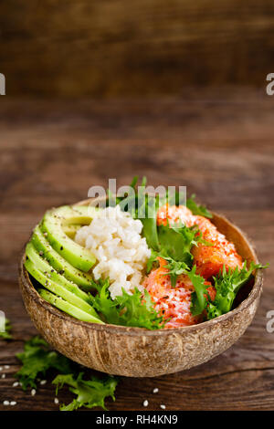 Hawaiian poke ciotola di noce di cocco con il salmone grigliato pesce, riso e avocado. Cibo sano Foto Stock