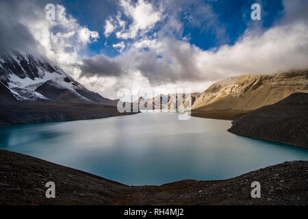 Vista panoramica sul lago Tilicho, l'innevamento del Tilicho picco nella distanza, scure nuvole monsoniche avvicinando Foto Stock