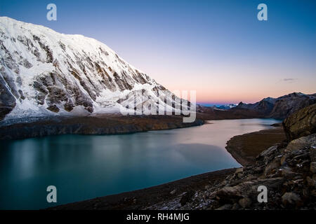 Vista panoramica sul lago Tilicho, l'innevamento del Tilicho picco nella distanza, la mattina presto prima del sorgere del sole Foto Stock