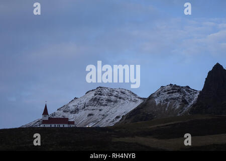 Una vista panoramica delle montagne e una piccola chiesa in Vik, Sud dell'Islanda. Foto Stock