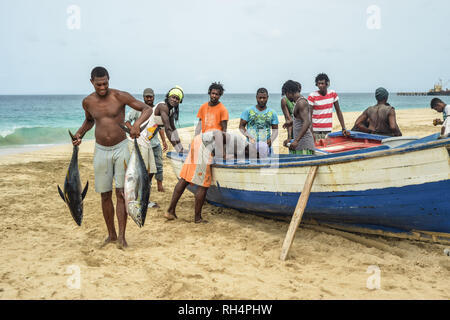 Capo Verde Isola di Maio: i pescatori di ritorno da un viaggio di pesca, sulla spiaggia di Porto Ingles (Vila do Maio). Lo scarico del pesce: uomo con due pesci nel suo Foto Stock