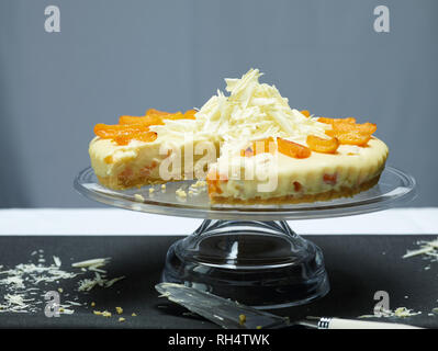 Albicocca e cioccolato bianco cheesecake con una fetta presa e una fetta di torta Foto Stock