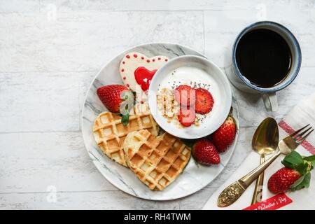 Il giorno di San Valentino la colazione a forma di cuore ad cialde yogurt granola tazza di fragole fresche, vista aerea Foto Stock