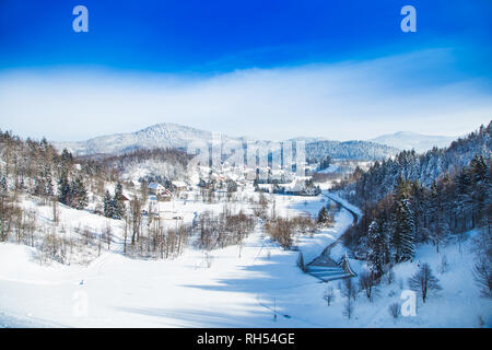 Il croato paesaggio di campagna in inverno, panorama della città di Lokve sotto la neve nella regione di Gorski kotar, montagne sullo sfondo Foto Stock