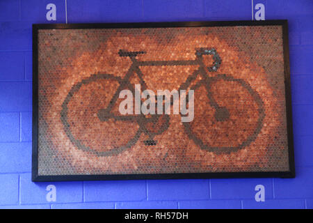 Una grande immagine di una bicicletta realizzata con pochi spiccioli appeso contro un blu muro di calcestruzzo di recupero. Foto Stock