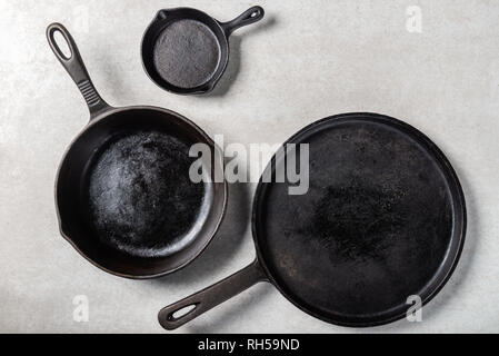 Diversi Ghisa padelle o Skillets per una sana cottura su sfondo grigio Foto Stock