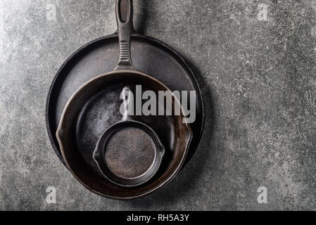 Diversi Ghisa padelle o Skillets per una sana cottura su sfondo grigio Foto Stock