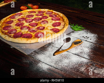 Una deliziosa pizza con salame su un bellissimo sfondo Foto Stock