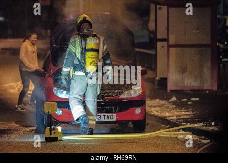 Un membro del servizio antincendio è visto in piedi guardando il motore di fumare. Una vettura ha preso fuoco stasera sulla B9096 in Tullibody. Fire & Rescue e la polizia erano sulla scena. Non ci sono stati feriti. Fire & Rescue portato sotto controllo l'incendio e mettere fuori. Foto Stock