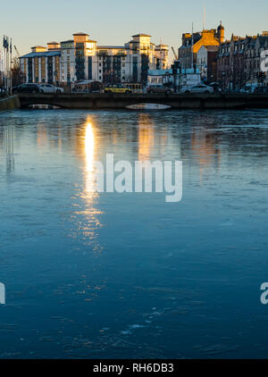 La Riva, Leith, Edimburgo, Scozia, Regno Unito, 1 febbraio 2019. Regno Unito: meteo fenomeno insolito di acqua congelata di Leith. Moderno appartamento edifici di Queen's Quay riflessa nella superficie ghiacciata del fiume Foto Stock