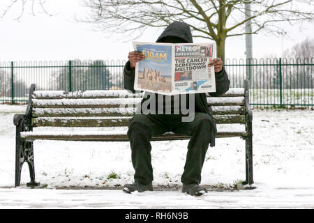 Londra, UK 1 Feb 2019 - Un uomo seduto su una panchina coperta di neve è visto leggendo una copia di oggi del metro in un North London park dopo una notte di nevicata nella capitale. Credito: Dinendra Haria/Alamy Live News Foto Stock