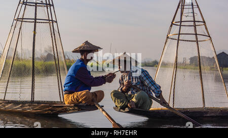 Lago Inle/ Myanmar- gennaio 12,2019: tradizionale di pescatori Intha prendendo una pausa sigaretta con cheroot sigari nelle prime ore del mattino sul lago Inl Foto Stock