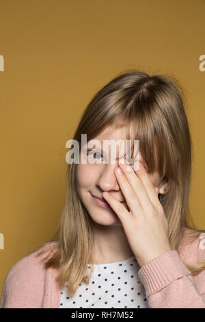Ritratto di tween sorridente ragazza occhio di copertura con la mano Foto Stock