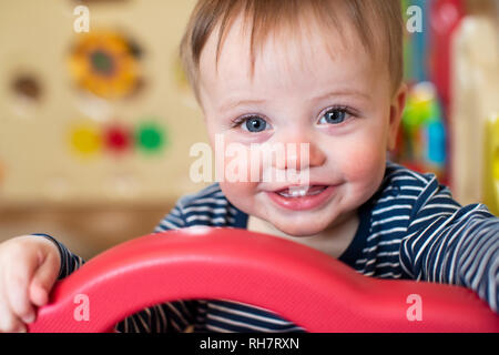 Ritratto di simpatici baby boy guardando fuori gioco la penna e sorridente in telecamera Foto Stock