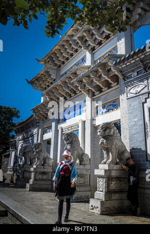 Donna guida turistica vestito in un tradizionale costume Naxi, porta principale di accesso di Um Residence, la residenza della famiglia um, la Città Vecchia di Lijiang, Yu Foto Stock