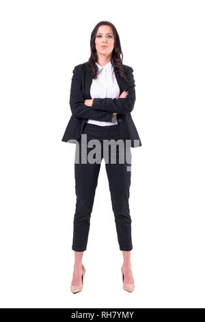 Vista frontale del fiducioso business donna in nero abito classico con bracci incrociati. Corpo pieno isolati su sfondo bianco. Foto Stock