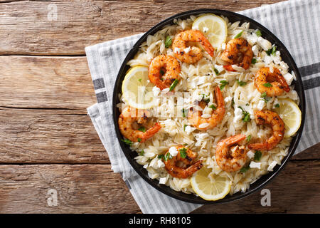 Cucina mediterranea pasta orzo con i gamberi alla griglia, il formaggio feta e limone close-up su una piastra sul tavolo. parte superiore orizzontale vista da sopra Foto Stock