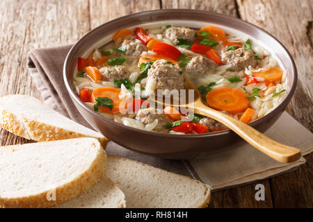 Hot ricca zuppa italiana con pasta orzo, polpette di pollo e verdure close-up in una ciotola sul tavolo orizzontale. Foto Stock