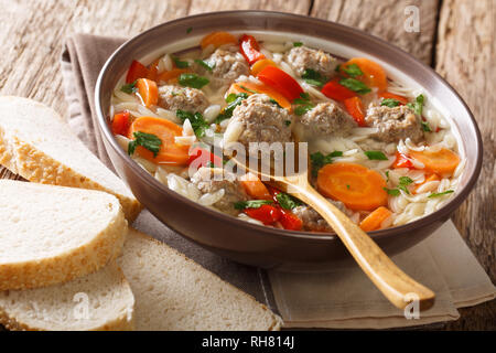 Tradizionale zuppa italiana con pasta orzo, polpette di pollo e verdure closeup in una piastra servita con pane fresco orizzontale. Foto Stock