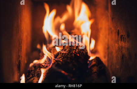 Bruciando legna e carbone nel camino. Caldo fuoco nel forno di scuro. La masterizzazione di pezzi di legno nel camino con parete scura di camino. Foto Stock