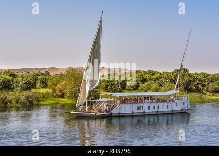 Imbarcazione a vela sul fiume Nilo vicino alla riva verde e il deserto, turisti rilassarsi sulla terrazza, Nilo, Egitto, 23 Ottobre 2018 Foto Stock