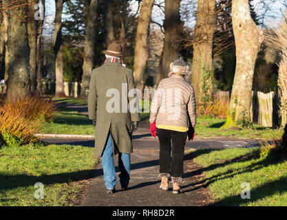 Persone di mezza età o senior giovane vestito in un caldo abbigliamento invernale con sciarpa e cappello camminare insieme su un percorso di paese in inverno nel Regno Unito. Foto Stock