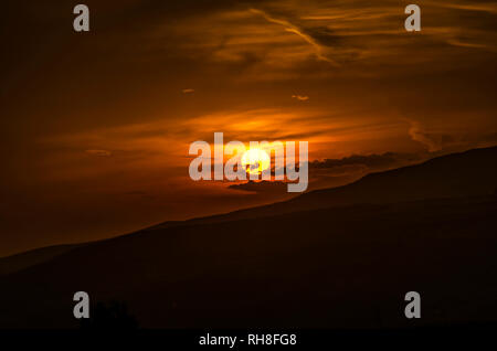 Bel Tramonto d'oro del disco solare nel cielo, tardo autunno sera sopra il terreno montuoso di Armenia Foto Stock
