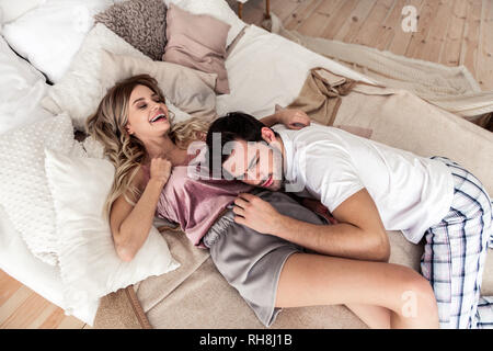 Dai capelli scuri bel giovane in una t-shirt bianco cercando felice Foto Stock