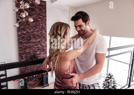 Bello barbuto brunette uomo in una t-shirt bianco cercando felice Foto Stock